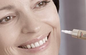 Жена нанася продукт на Eucerin на лявата си буза.