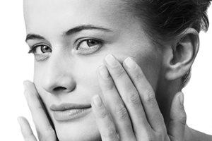 Жена докосва лицето си.