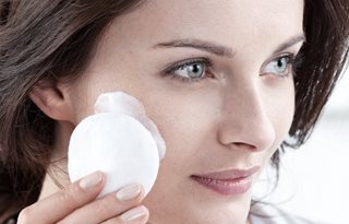 Жена нанася почистващо мляко с памучен тампон