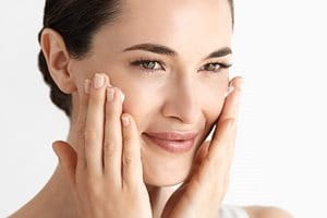 Жена докосвате лицето си с лявата си ръка.