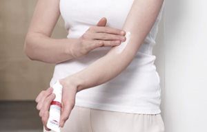 Жена нанася Eucerin AtopiControl Интензивен успокояващ крем върху сгъвката на ръката си.