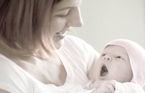 Жена държи новородено в ръцете си.