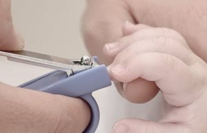Майка изрязва ноктите на бебето си с нокторезачка