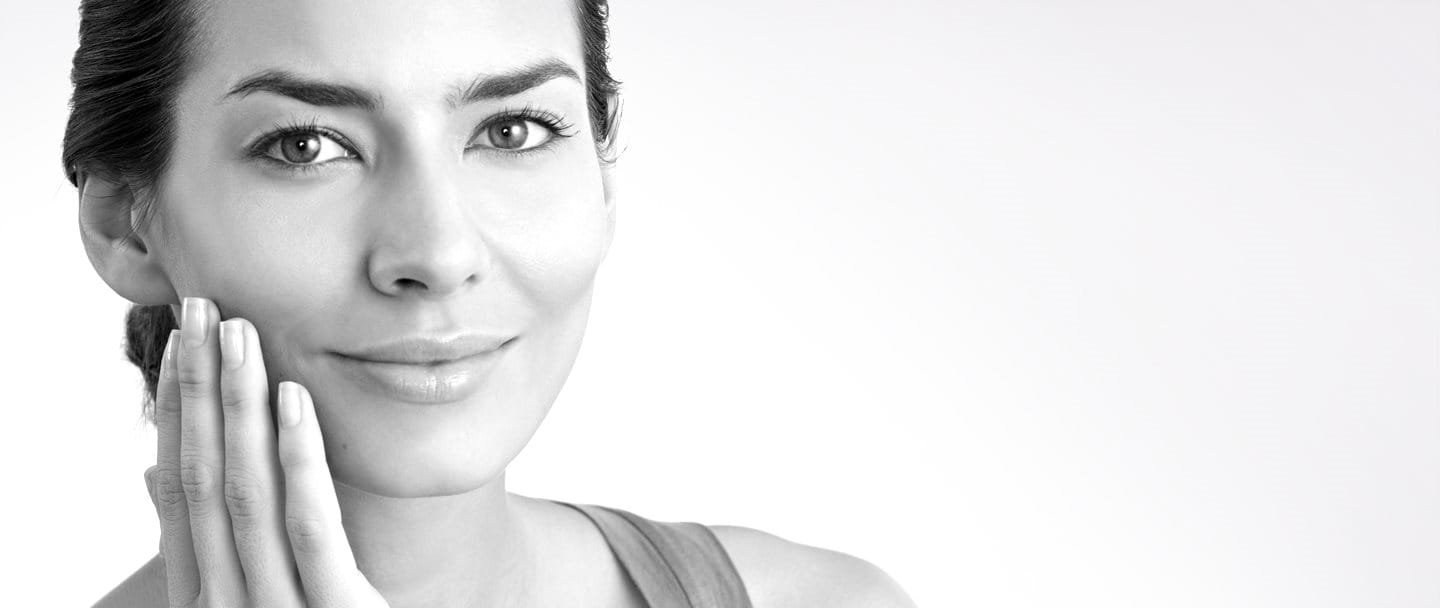 Жена на средна възраст докосва дясната си буза с ръка