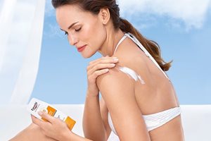 Жена, която нанася слънцезащитен продукт върху ръката си 